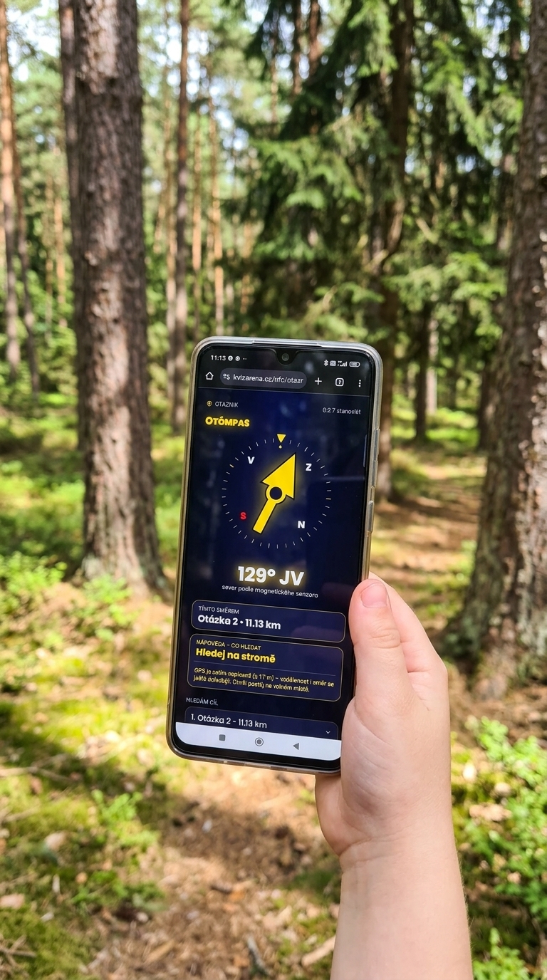 Ruka s telefonem v lese ukazuje kompas a navigaci ke stanovišti