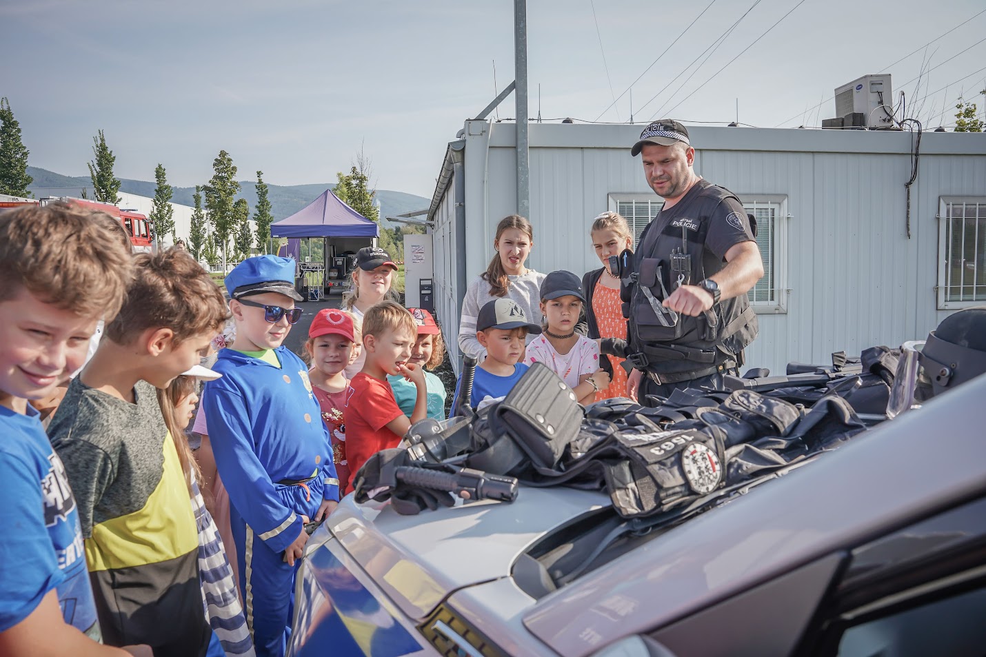 Policista ukazuje dětem výbavu složek IZS